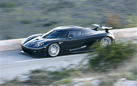 Черный Koenigsegg суперкар в скорости