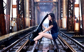 Девочка сидит на железнодорожных играть на гитаре, мост