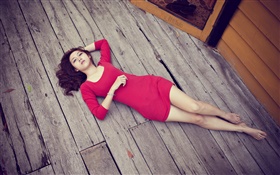Азиатская девушка лежала на деревянном полу, красное платье