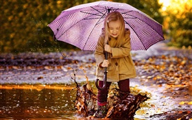 Милая маленькая девочка, играй воду, зонтик